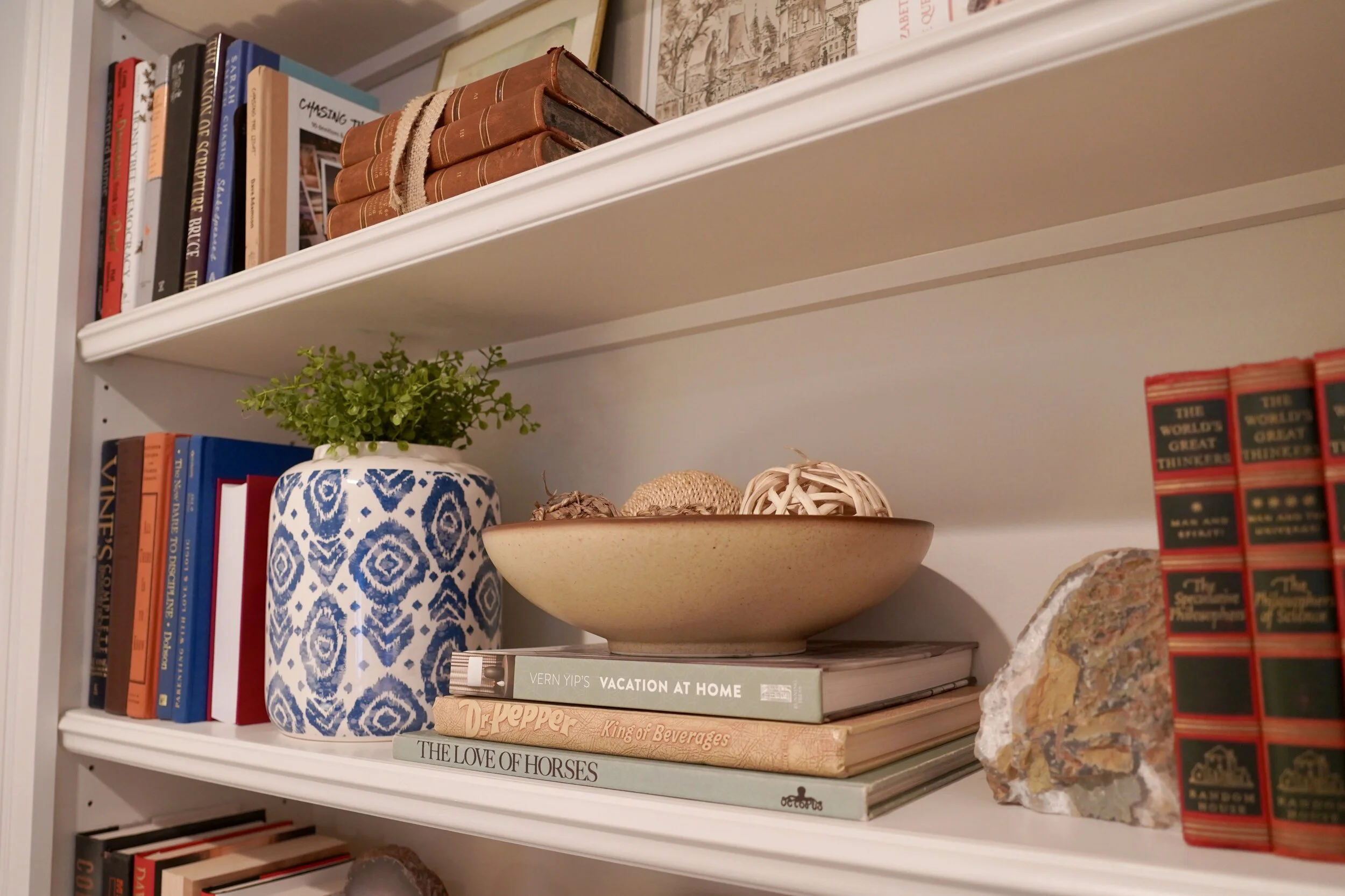 Close-up of a styled shelf with ceramics, books and greenery